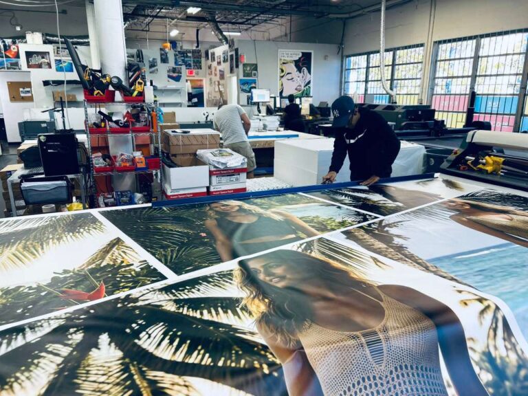 Production team reviewing large printed marine artwork on a worktable
