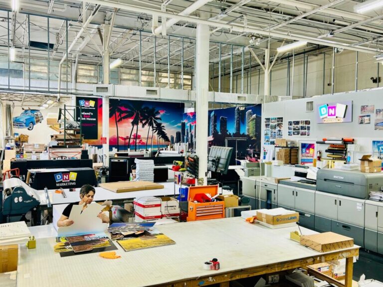 Printing production floor with wide-format printers, worktables, and finished graphics