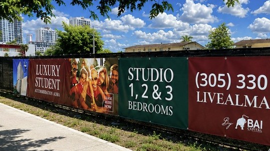 Large-format printed construction fence banner with project branding and leasing information