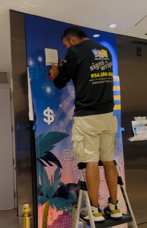 DNA installer applying Tech and Invest Miami event graphics